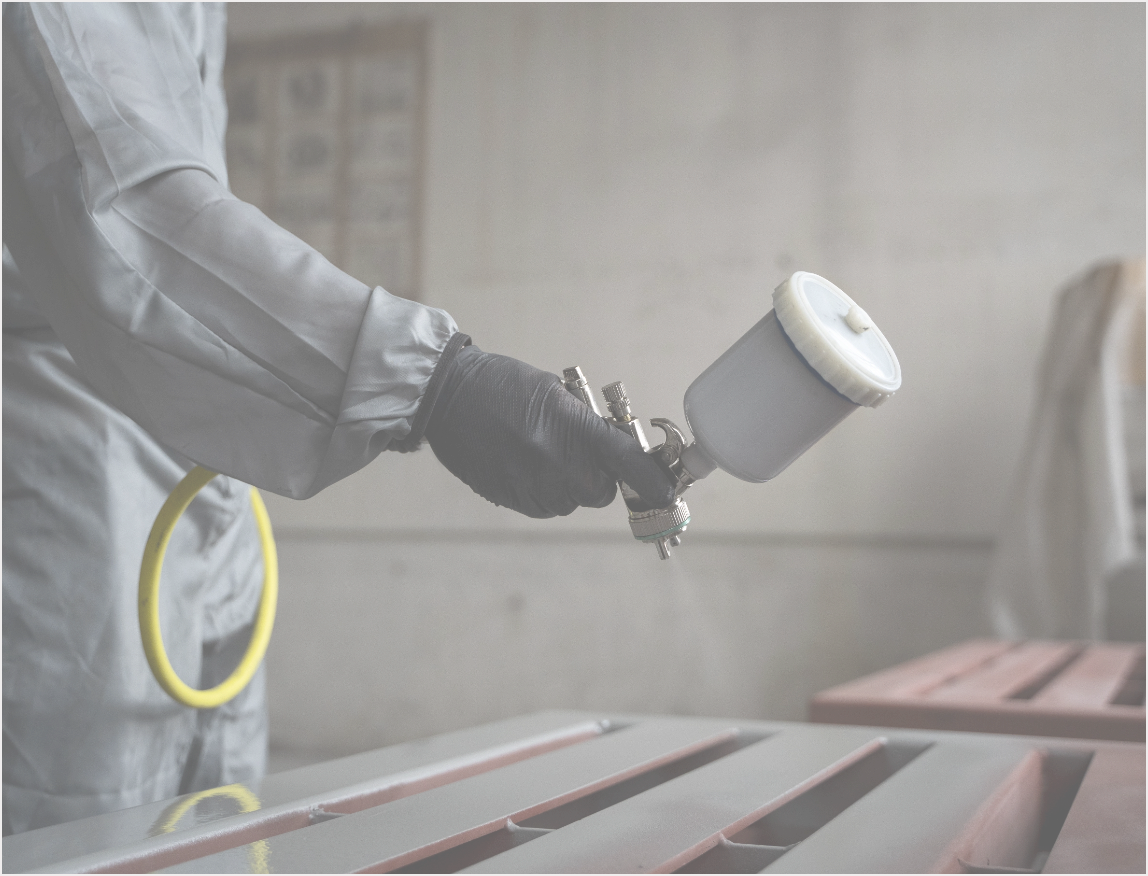 side-view-worker-spraying-powder-paint-from-gun@2x